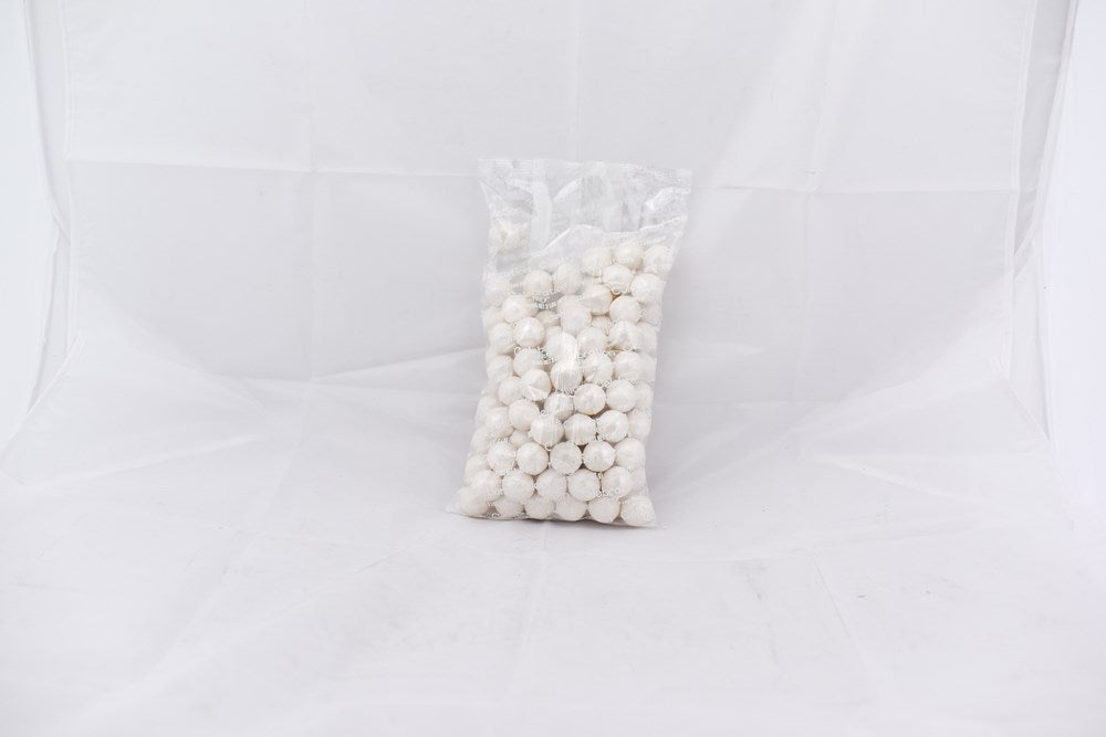 Clear plastic bag filled with small shiny white spherical gumballs against a plain white background.