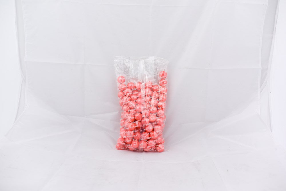 Clear plastic bag filled with shiny pastel coral-colored round gumballs.
