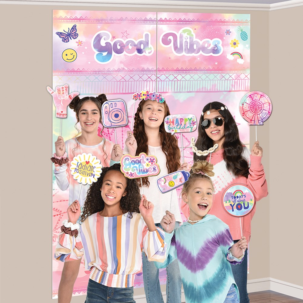Pastel pink and purple festival scene setter backdrop with "Good Vibes" text and 16 colorful photo props including flowers,.