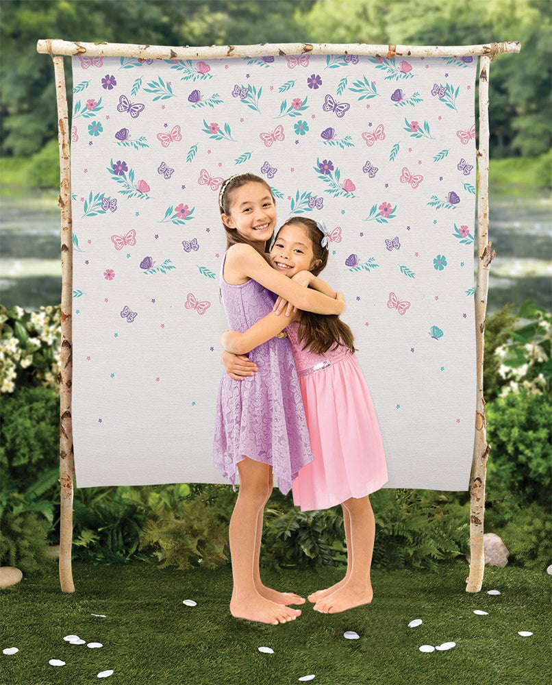 White canvas backdrop with pastel butterflies and flowers, hanging from a natural wooden frame outdoors.