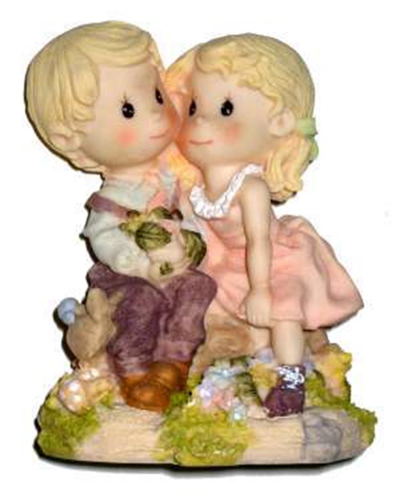Polystone figurine of a blonde boy and girl sitting closely with the girl kissing the boy’s cheek, detailed with soft pastel