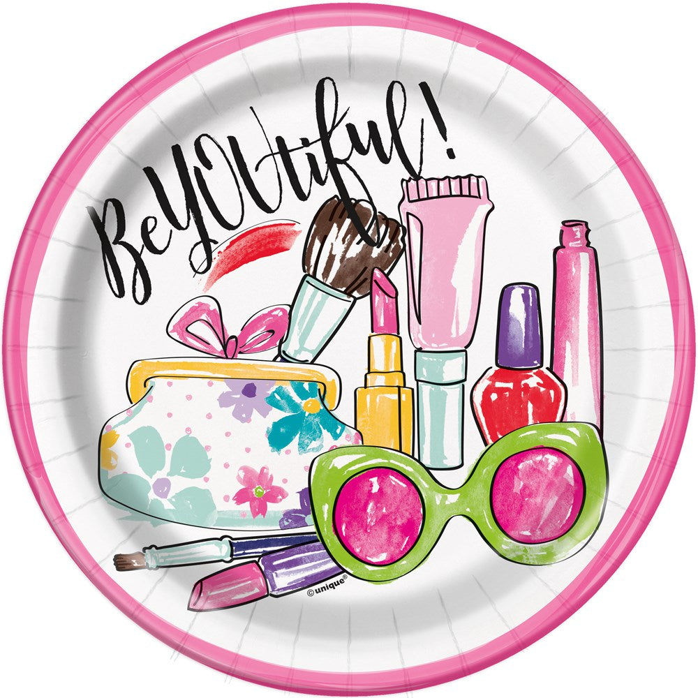 Round paper plate with pink rim featuring colorful spa-themed illustrations including sunglasses, makeup brushes, nail.