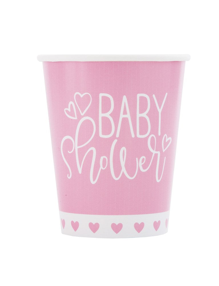 Pink paper cup with white "Baby Shower" text, heart illustrations, and a border of small hearts at the base.