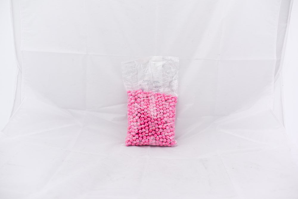 Clear plastic bag filled with small bright pink round beads against a white background.