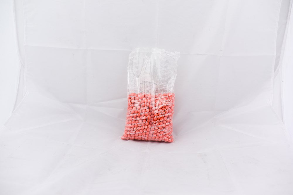 Clear plastic bag with small round coral-colored pellets inside against a white background.