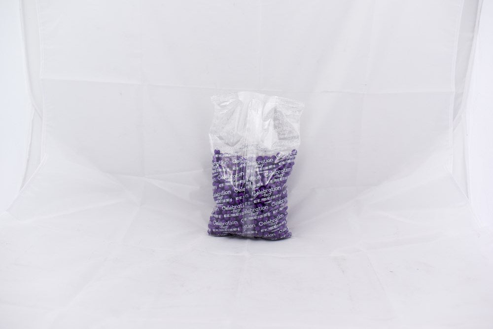 Transparent plastic bag filled with small dark purple SiXLets pellets on a white background.