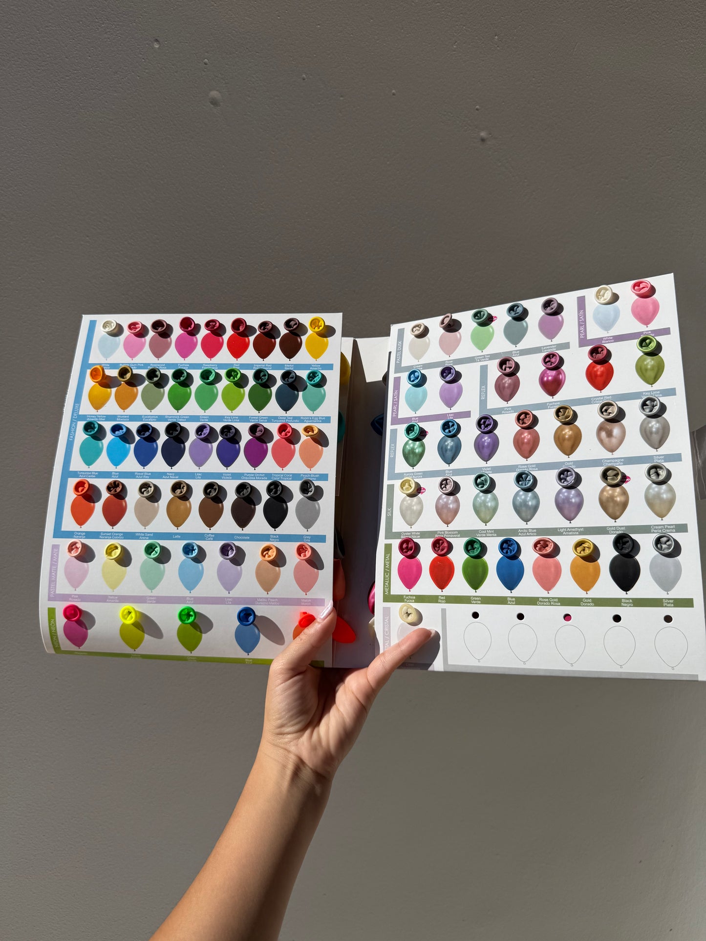 Sheet of colorful stickers held by a hand against a gray background