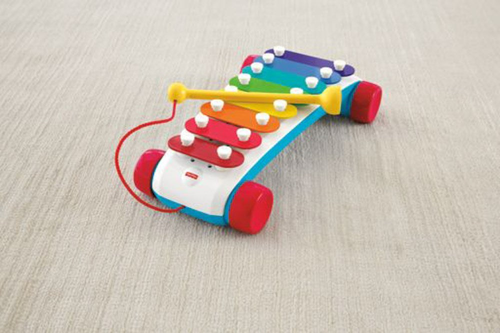 Colorful wooden xylophone with eight graduated metal bars in red, orange, yellow, green, blue, indigo, and violet on a blue.