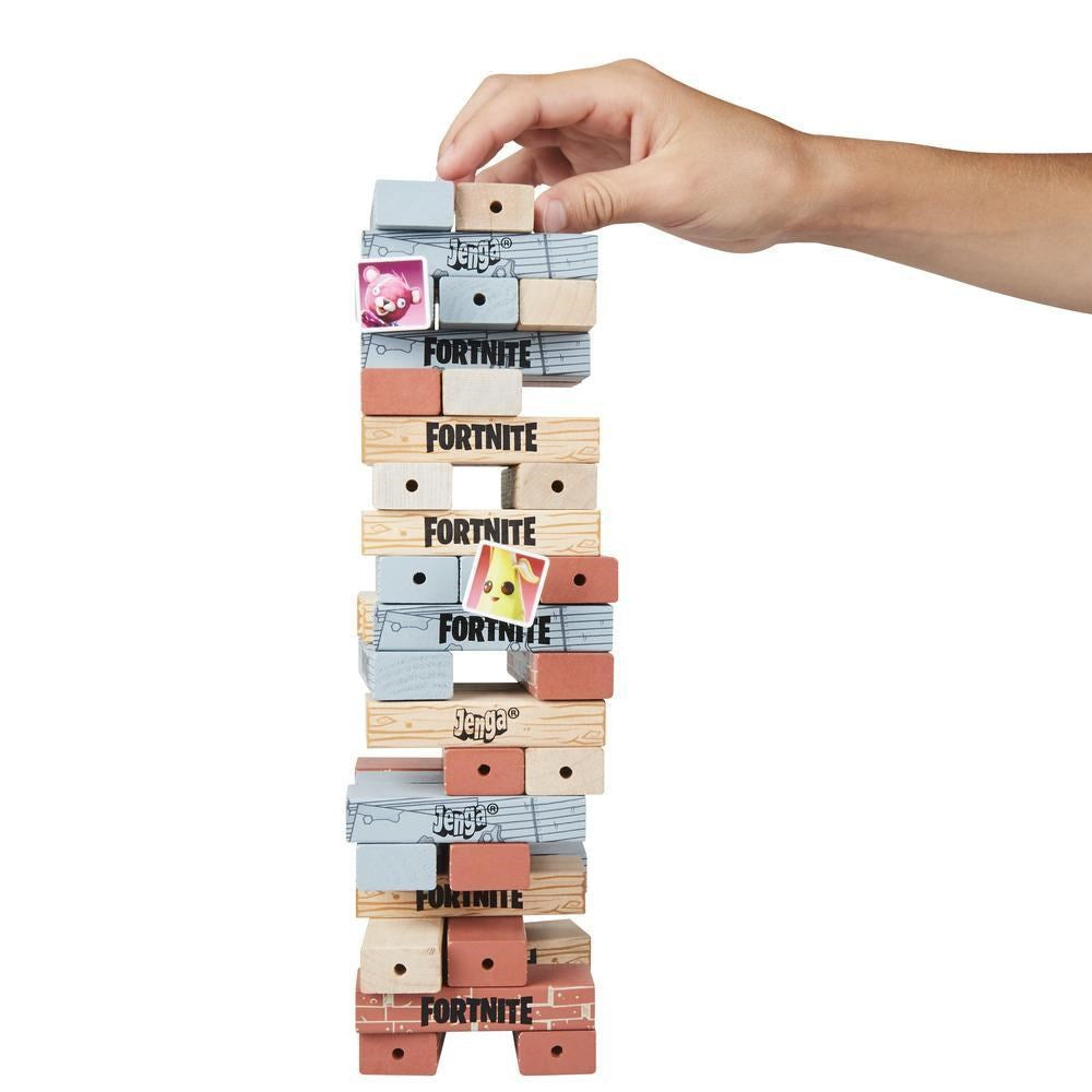 Stacked wooden Fortnite Jenga blocks in natural, gray, and orange tones with black logos and designs, hand removing a block.