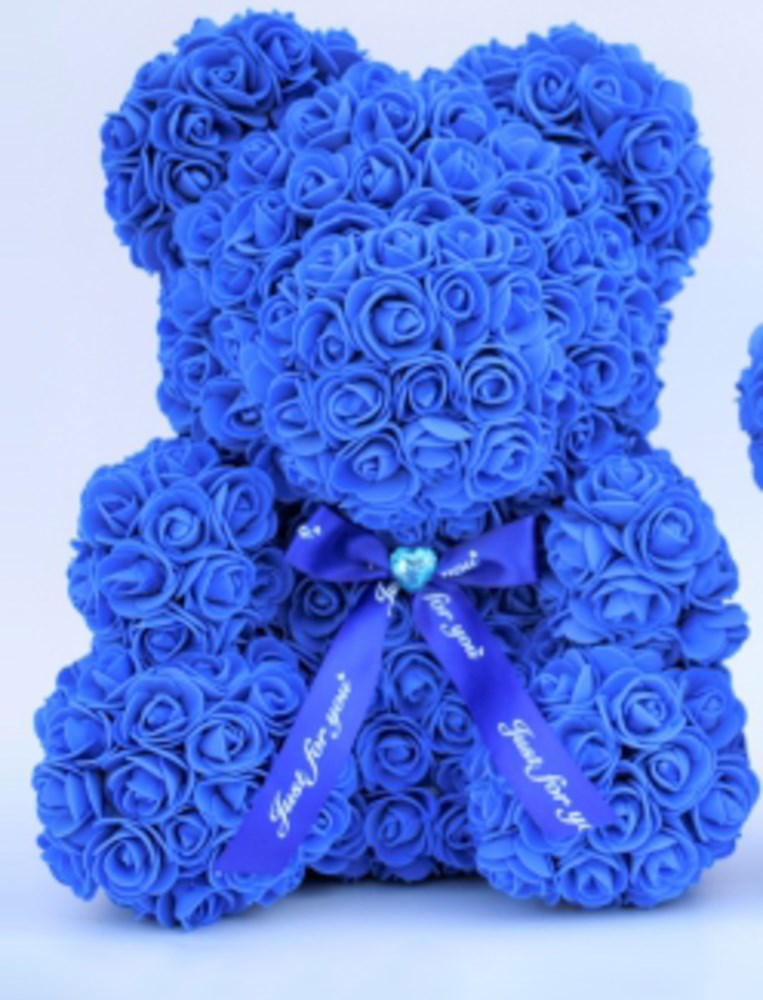 Sapphire blue teddy bear made entirely of small foam roses with a decorative blue ribbon and heart charm around its neck.