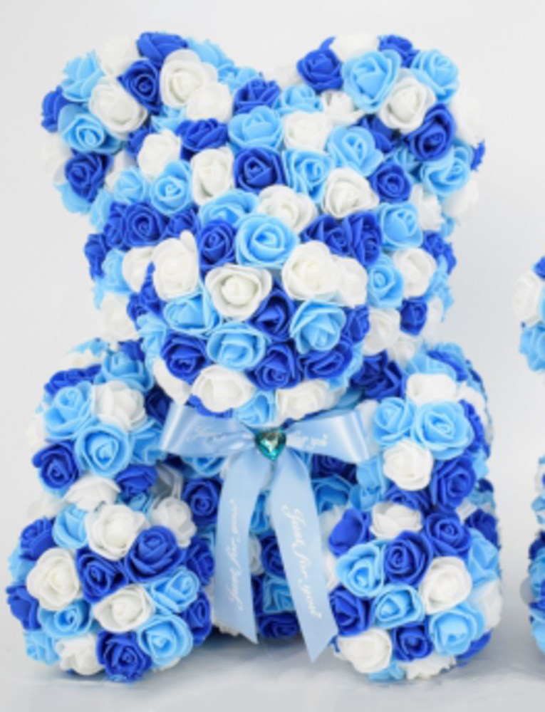 15-inch teddy bear made of foam roses in white, light blue, and royal blue with a sheer white bow around its neck.