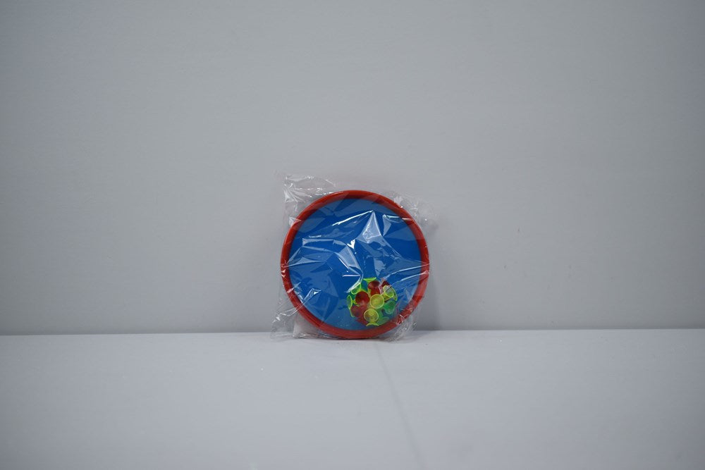 Blue fabric catch ball paddles with red plastic rims and a green ball attached by a string, packaged in clear plastic.