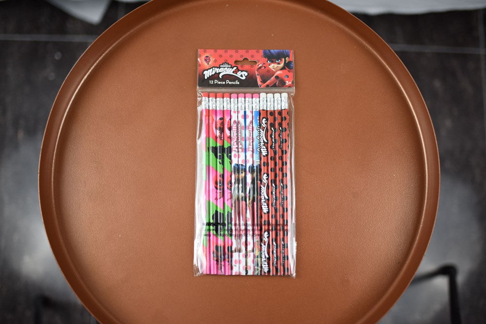 Set of 12 Miraculous Ladybug-themed wooden pencils with red, blue, and black patterned designs in clear plastic packaging.