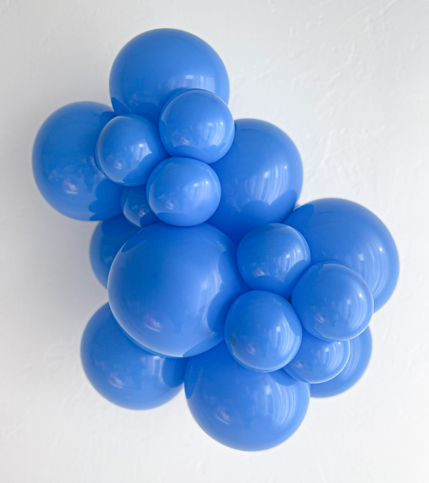 Cluster of shiny blue latex balloons in various sizes clustered together against a white background.