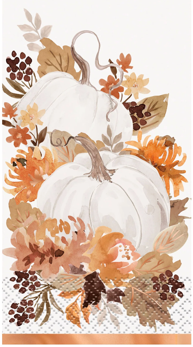 White pumpkins surrounded by orange and brown autumn leaves and flowers on a decorative napkin.