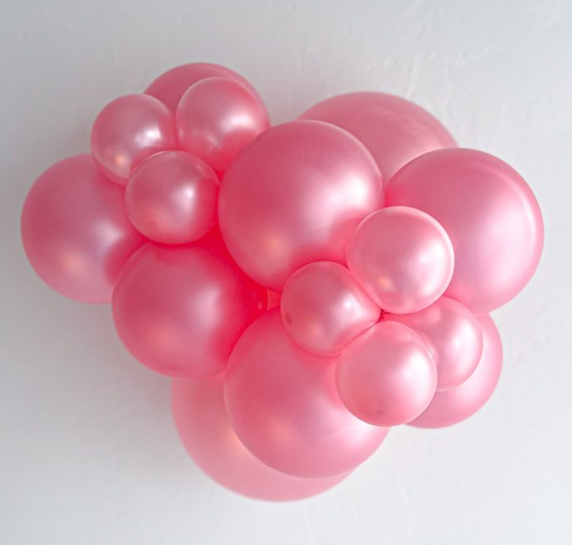 Cluster of pearlized pink latex balloons with shimmering metallic finish in various sizes.