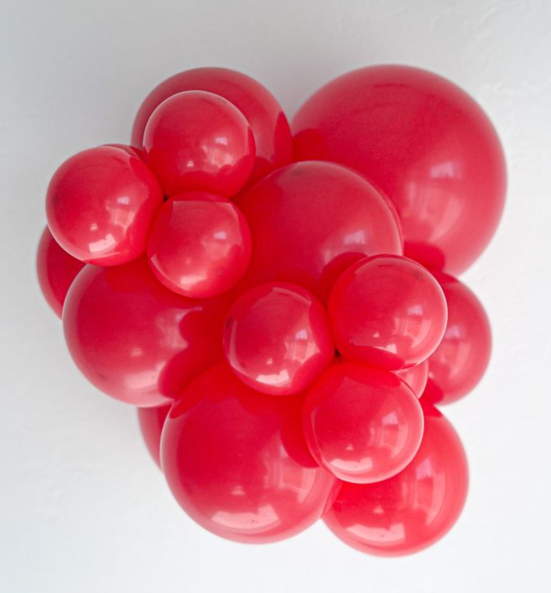 Cluster of shiny red latex balloons in various sizes, inflated and grouped tightly against a white background.