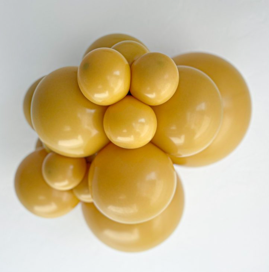 Cluster of shiny mustard yellow 5-inch round latex balloons tightly grouped together.