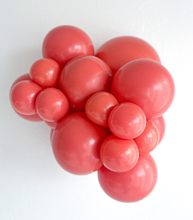 Cluster of shiny red latex balloons in varying sizes, inflated and grouped together.