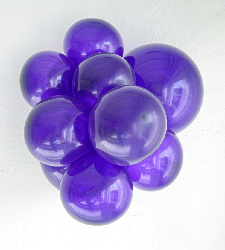 Cluster of glossy purple latex balloons inflated to varying sizes with a reflective surface.