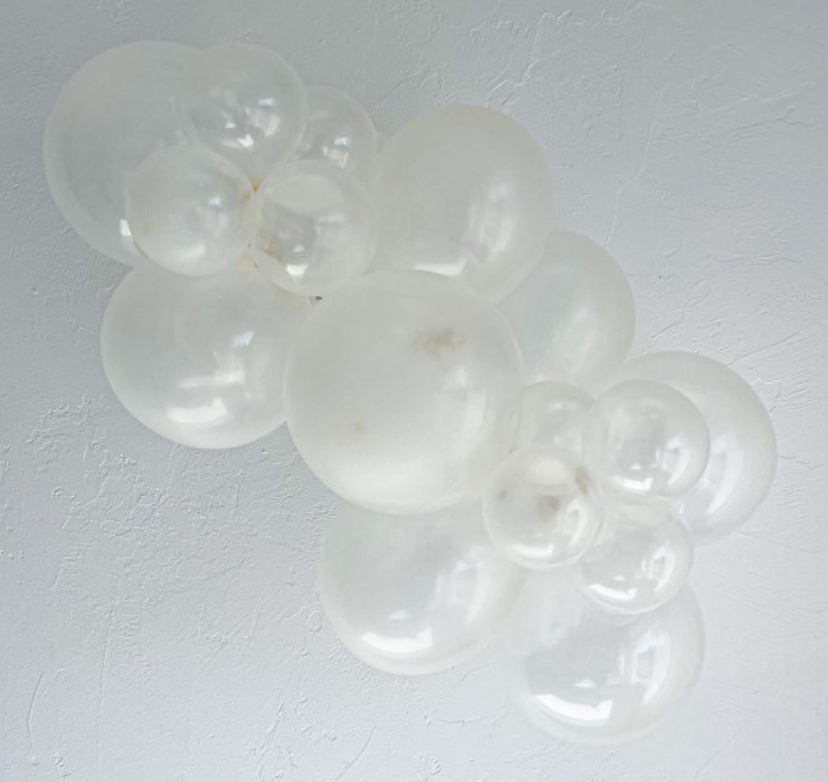 Cluster of clear, shiny latex balloons in various sizes, arranged in a decorative garland.