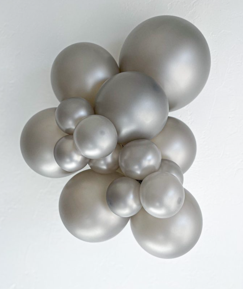 Cluster of metallic silver latex balloons in varying sizes forming a decorative arrangement.