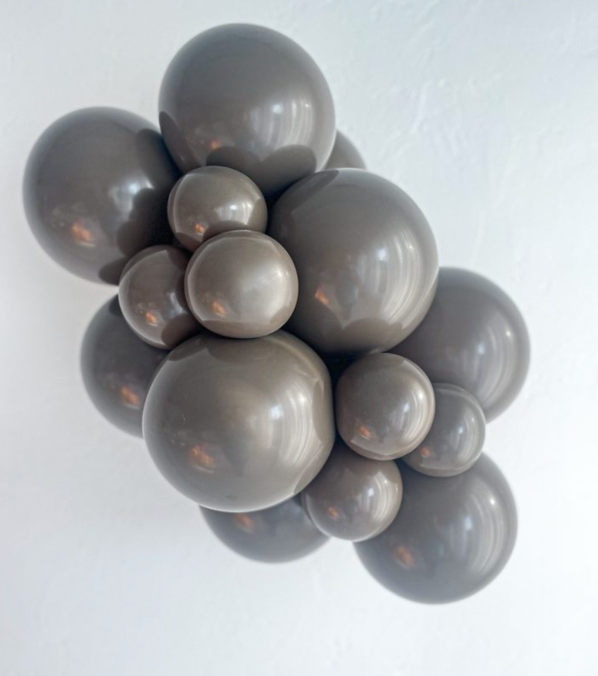 Cluster of glossy brown latex balloons in varying sizes arranged closely together.