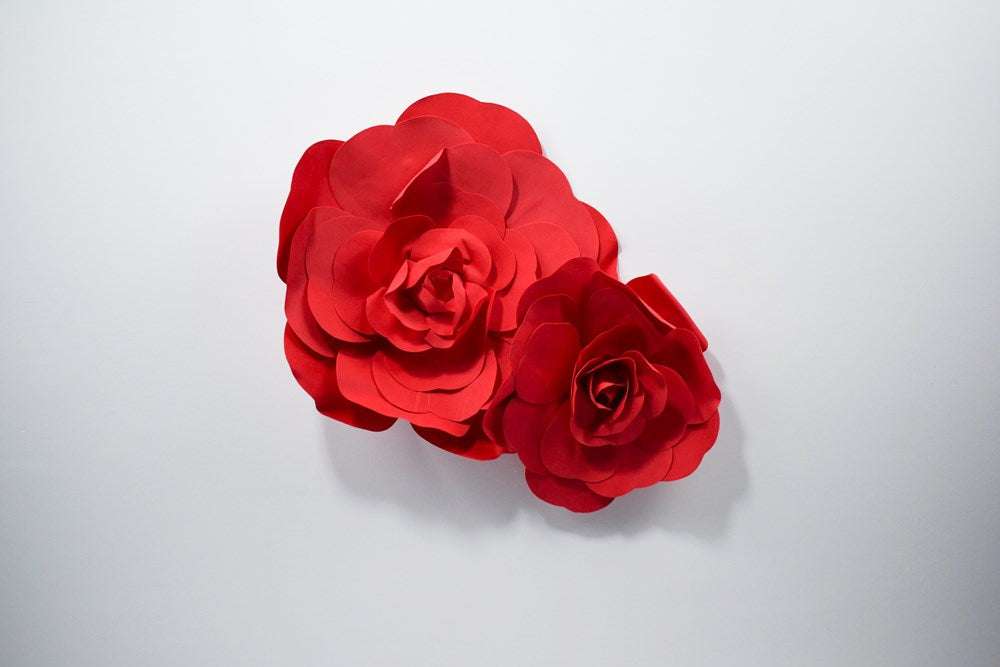 Two vibrant red decorative paper wall flowers in 12-inch and 16-inch sizes with layered petals.