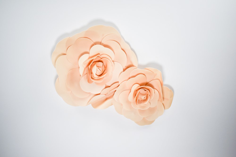 Two taupe decorative wall flowers in 12-inch and 16-inch sizes with layered petals.