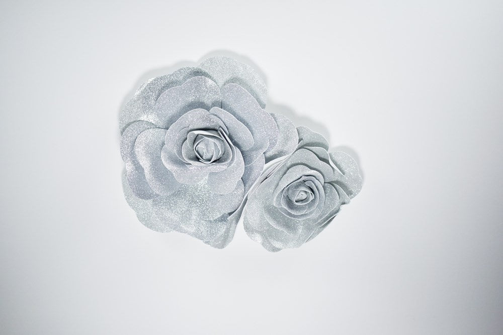 Set of two silver metallic wall flowers with layered petals, one 16 inches and one 12 inches in diameter.