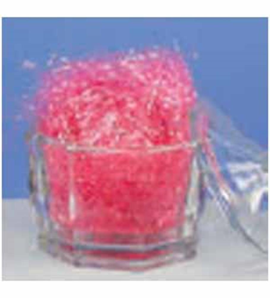 Clear faceted glass container filled with bright pink shredded decorative grass against a blue background.