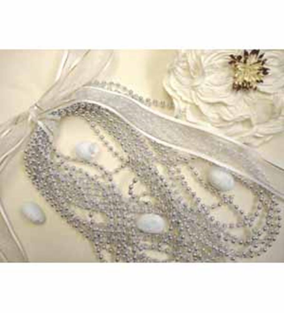 Strands of small silver 4mm round beads with a shiny finish, loosely coiled on a neutral fabric background with a decorative