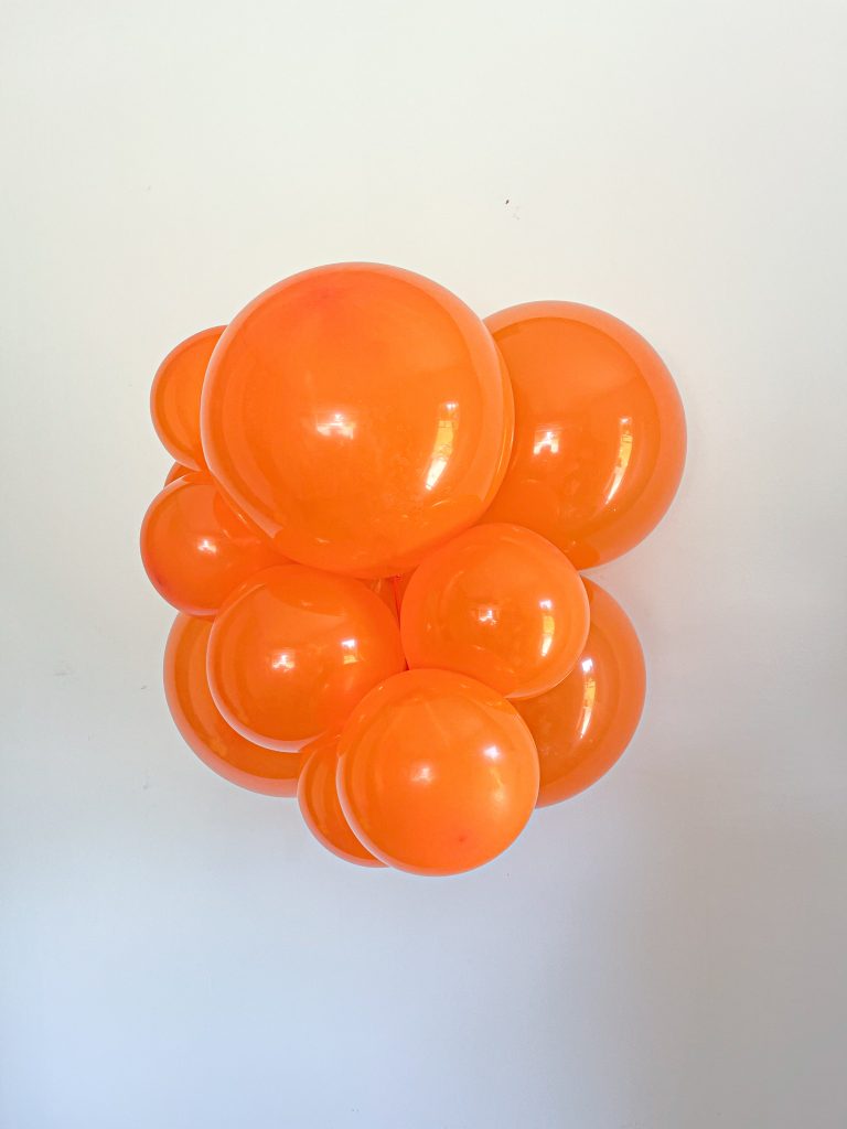 Tuftex Crystal Tangerine latex balloon color cluster showing the shade across multiple balloon sizes