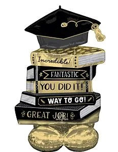 Stacked foil balloon shaped like graduation cap atop four books in black, white, and gold with celebratory text.