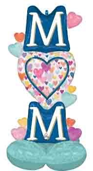 49-inch foil balloon with stacked letters "M" in navy blue, colorful heart patterns, and pastel heart accents.