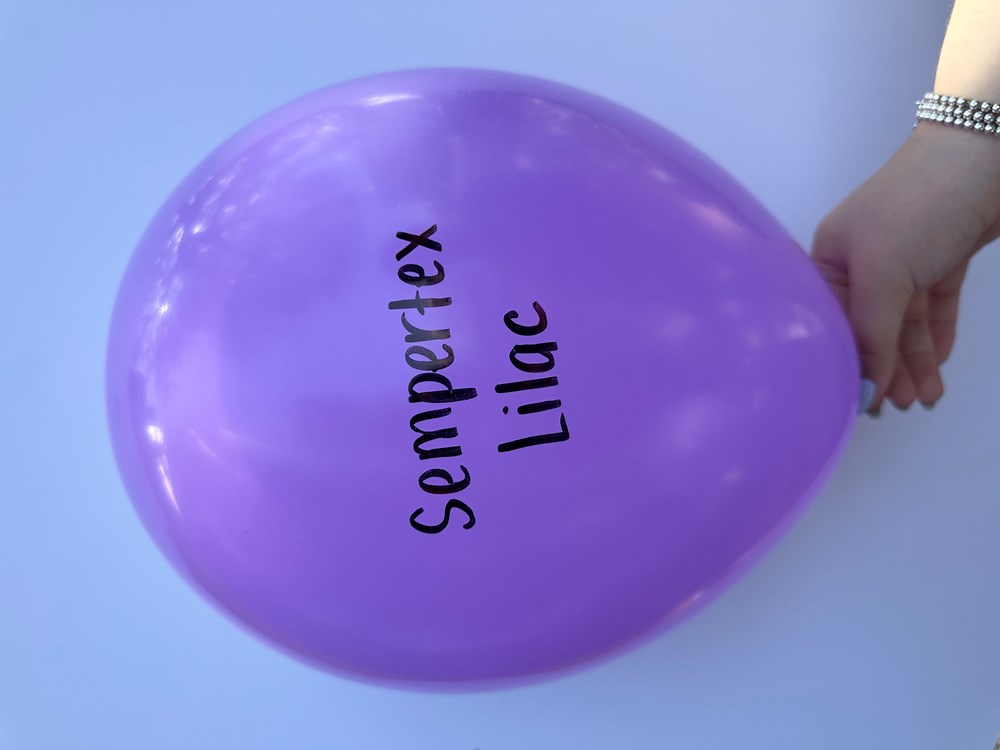 Round lilac latex balloon inflated with Sempertex Lilac printed in black letters, held by hand.