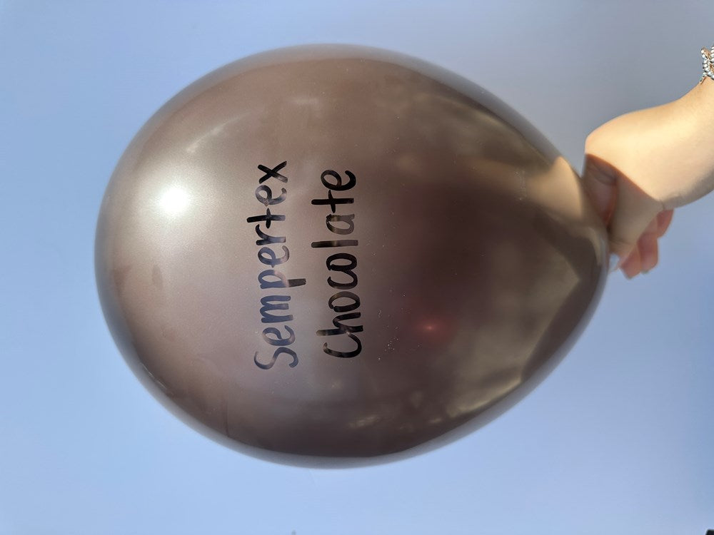 Chocolate brown 11 inch latex balloon with Sempertex Chocolate logo, inflated and held by hand against blue sky.