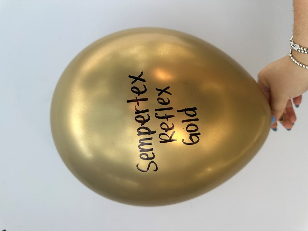 Shiny gold latex balloon with Sempertex Reflex Gold printed in black, held by hand.