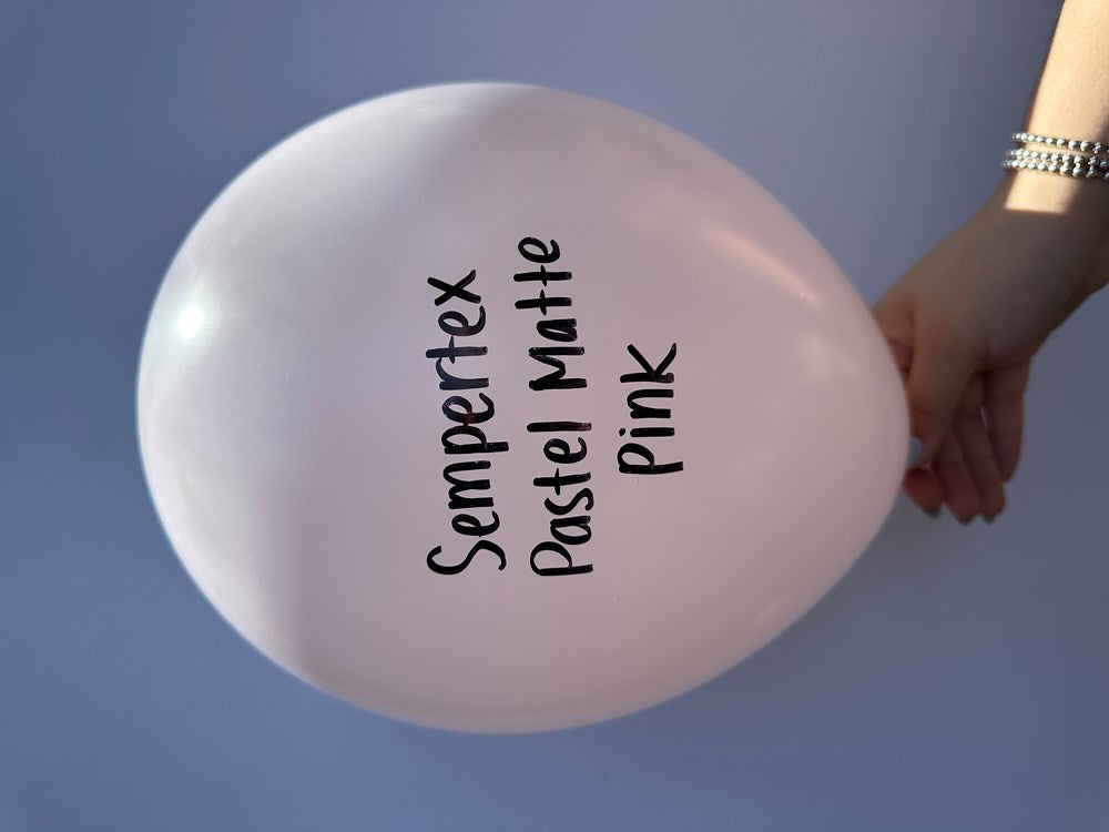 Light pastel pink latex balloon with a matte finish, round 11-inch shape, held by hand.