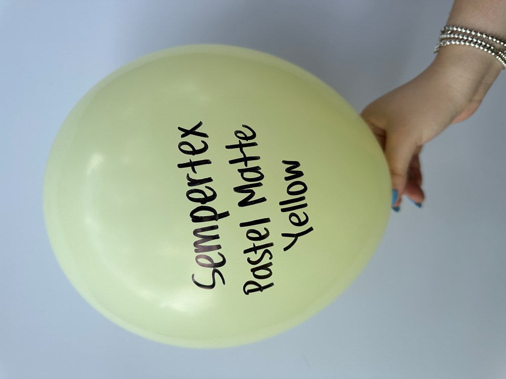 Glossy pastel matte yellow 11-inch latex balloon held by hand with text printed on surface.