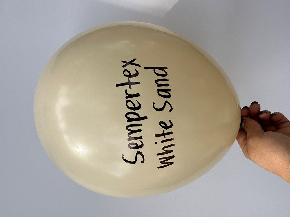 Round 11-inch latex balloon in white sand color with black "Sempertex White Sand" text, held by hand.