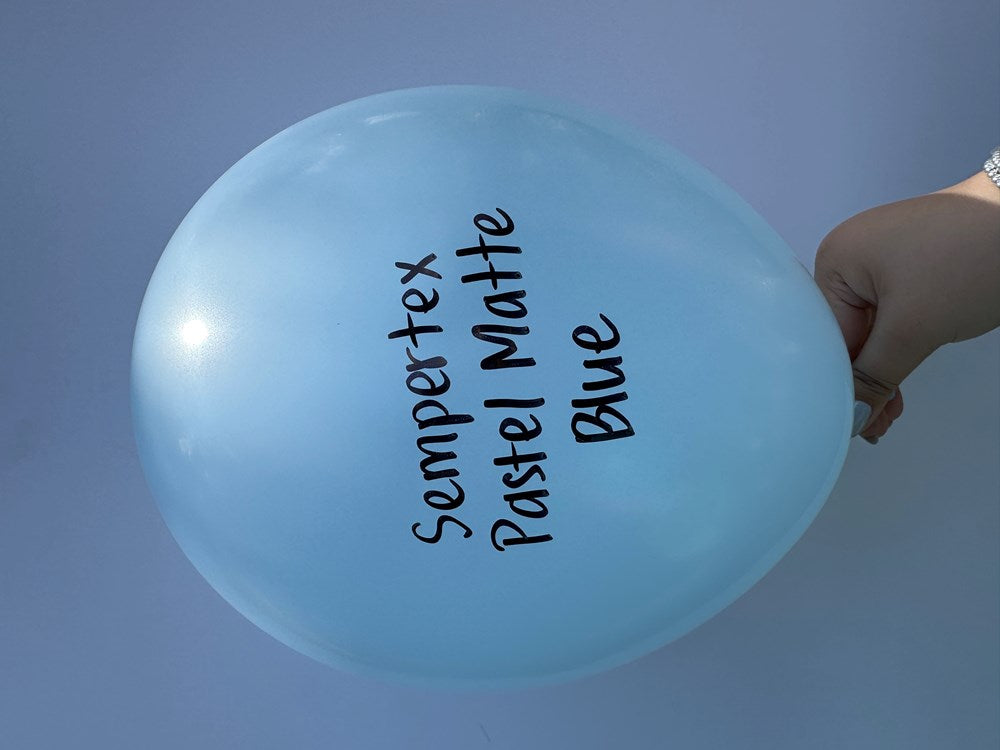 Light blue, round latex balloon with black printed text, held by a hand on a blue background.
