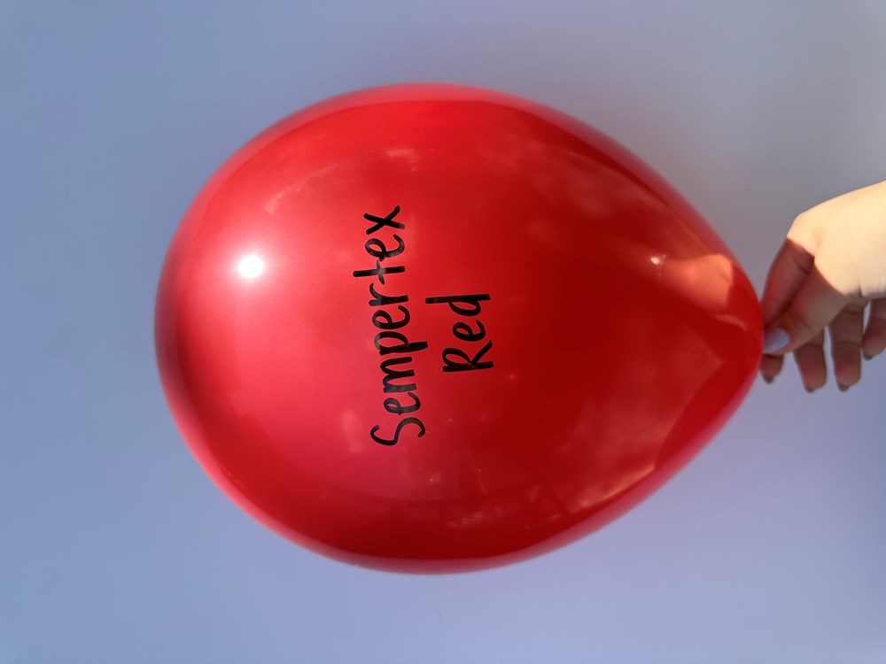 Bright red latex balloon inflated to 18 inches with black "Sempertex Red" text, held by hand.