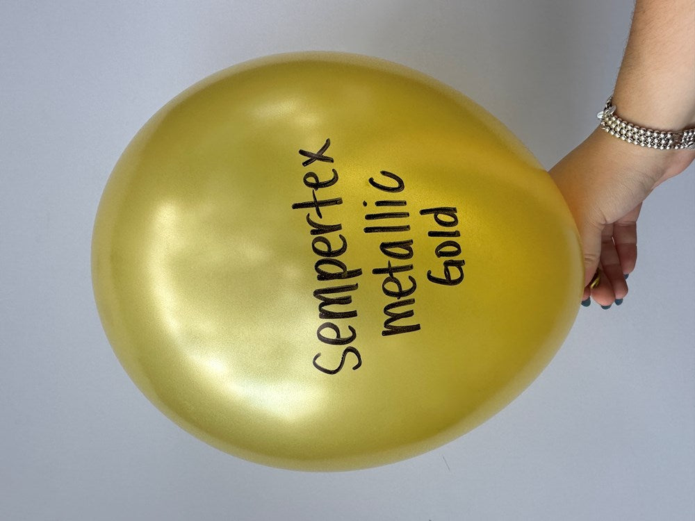 Metallic gold 18-inch round latex balloon with Sempertex metallic gold text held by hand.