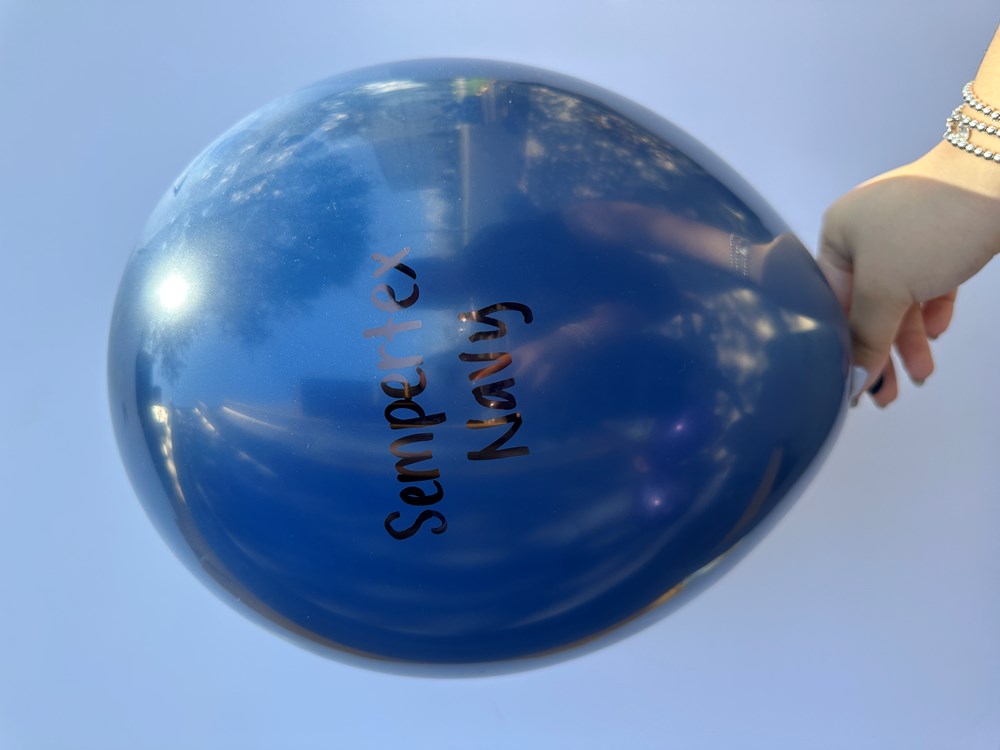 Glossy navy blue latex balloon, 18-inch round shape, printed with black "Sempertex Navy" text, held by hand.