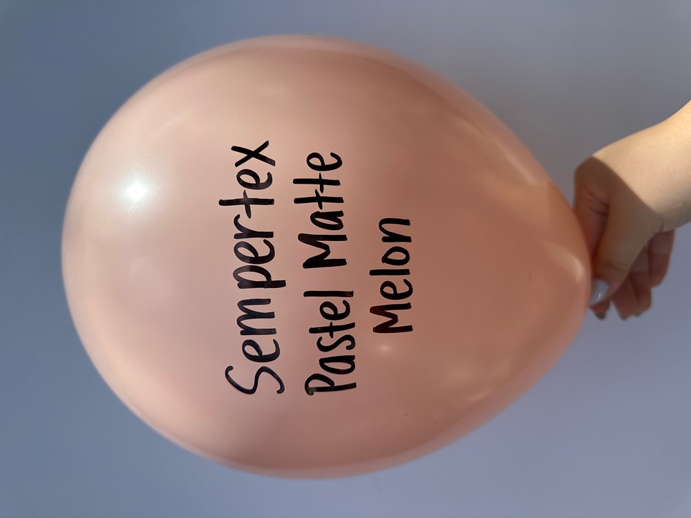 Large round pastel matte melon-colored latex balloon with Sempertex branding, held by hand.