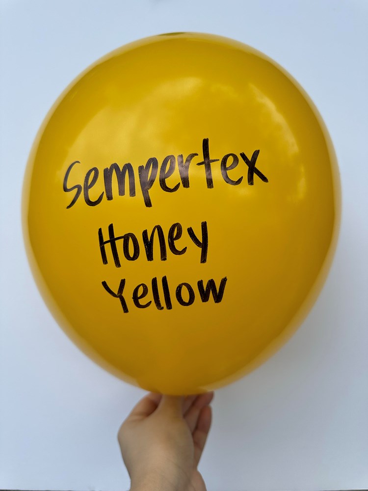 Bright honey yellow 18-inch latex balloon with black Sempertex logo and text held by hand.