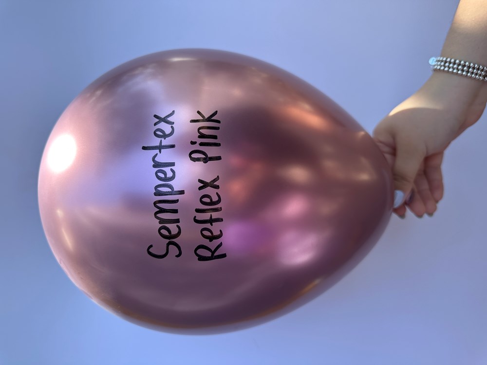 18-inch reflex pink latex balloon with glossy, metallic finish held by hand against a blue background.