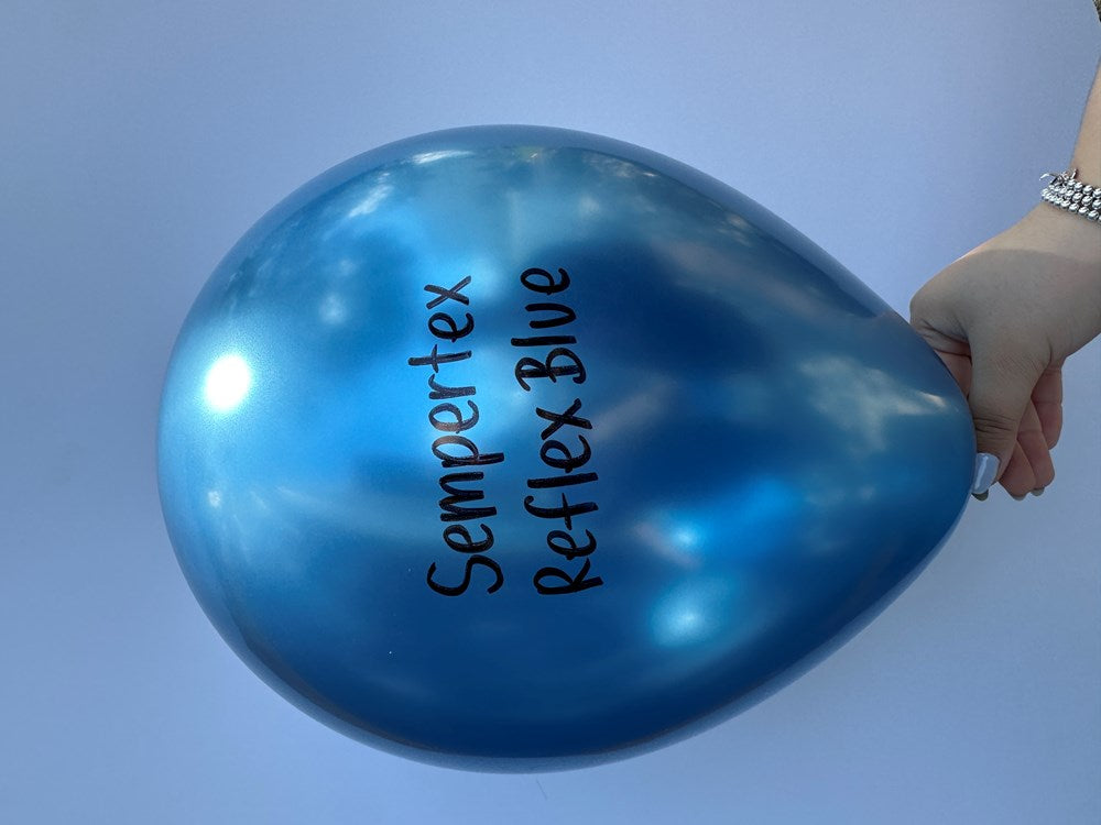 Shiny deep blue latex balloon inflated, held by hand, with Sempertex Reflex Blue text printed on surface.