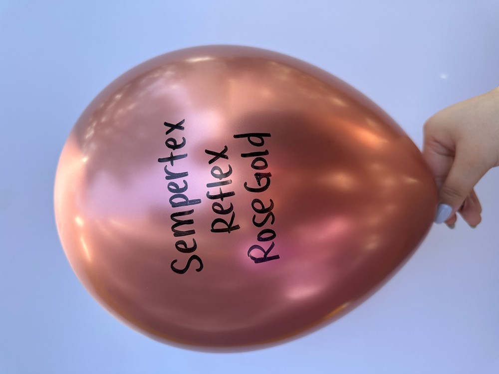 Glossy rose gold 18-inch latex balloon with Sempertex Reflex branding, inflated and held by hand.